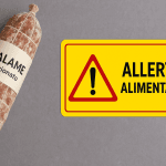Salame stagionato richiamato per frammenti di spugna accanto a cartello allerta alimentare