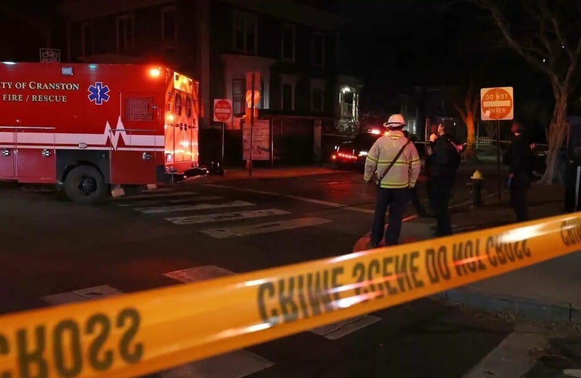 Scena del crimine con polizia e ambulanza dopo la Sparatoria alla Brown University: 2 morti e 20 feriti. Nastro giallo delimitatorio in primo piano.